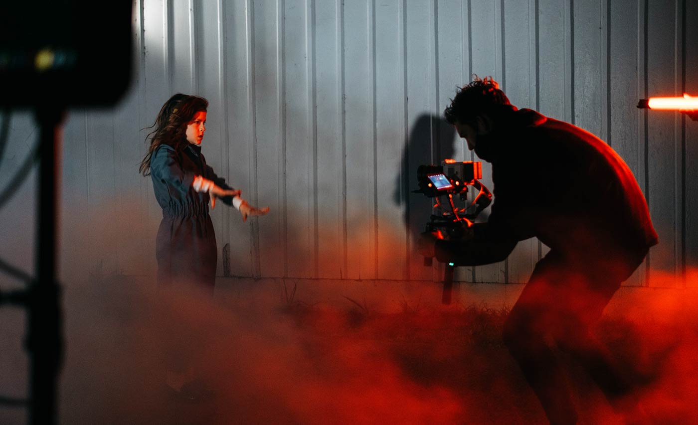 Mann filmt Frau im rotem Rauch für's Tablet